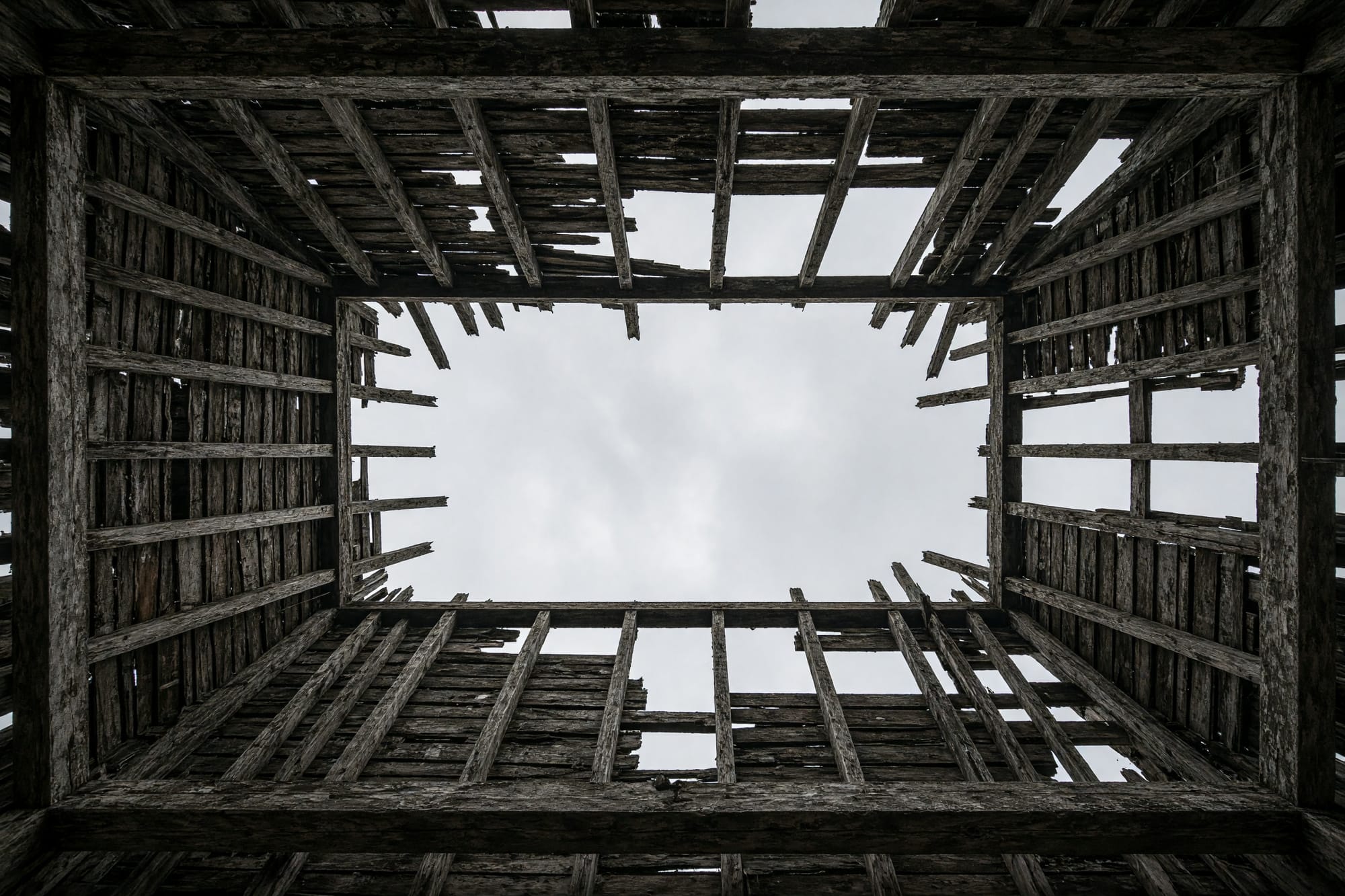 A collapsed roof structure seen from below, timbers against sky