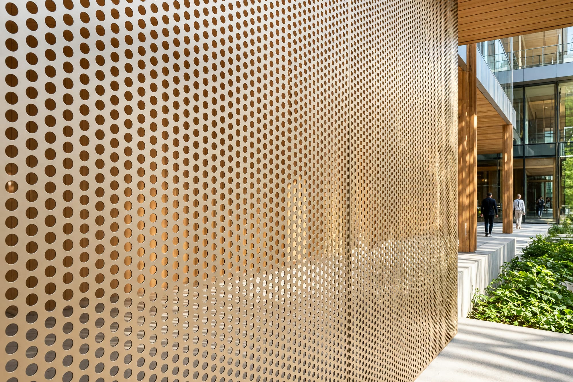 Perforated metal cladding in close view with sunlight passing through onto the structure behind