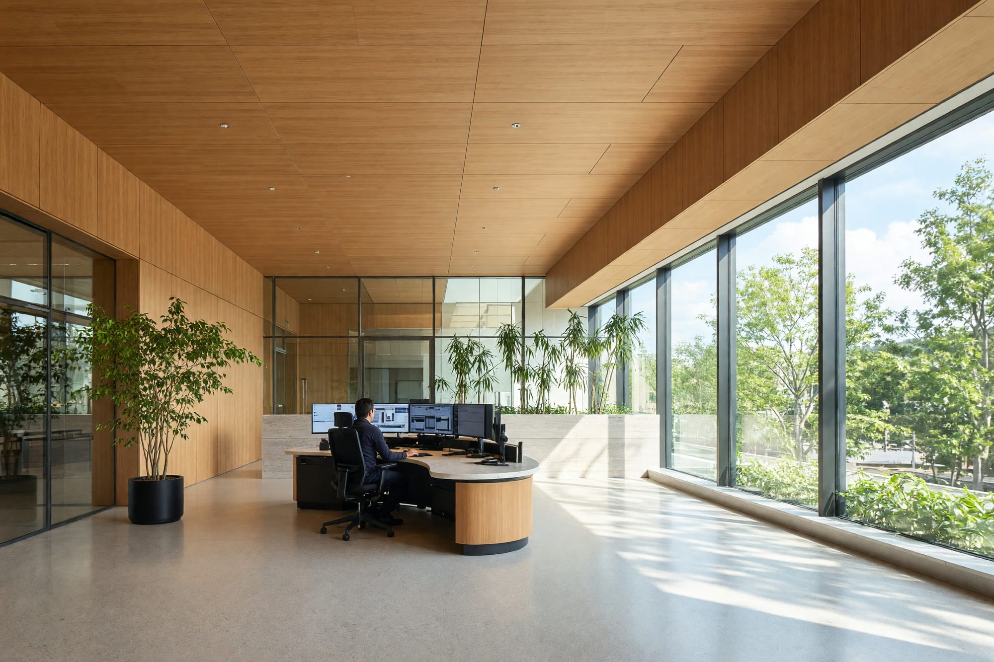 A calm daylit control room with one operator at distance and screens abstracted