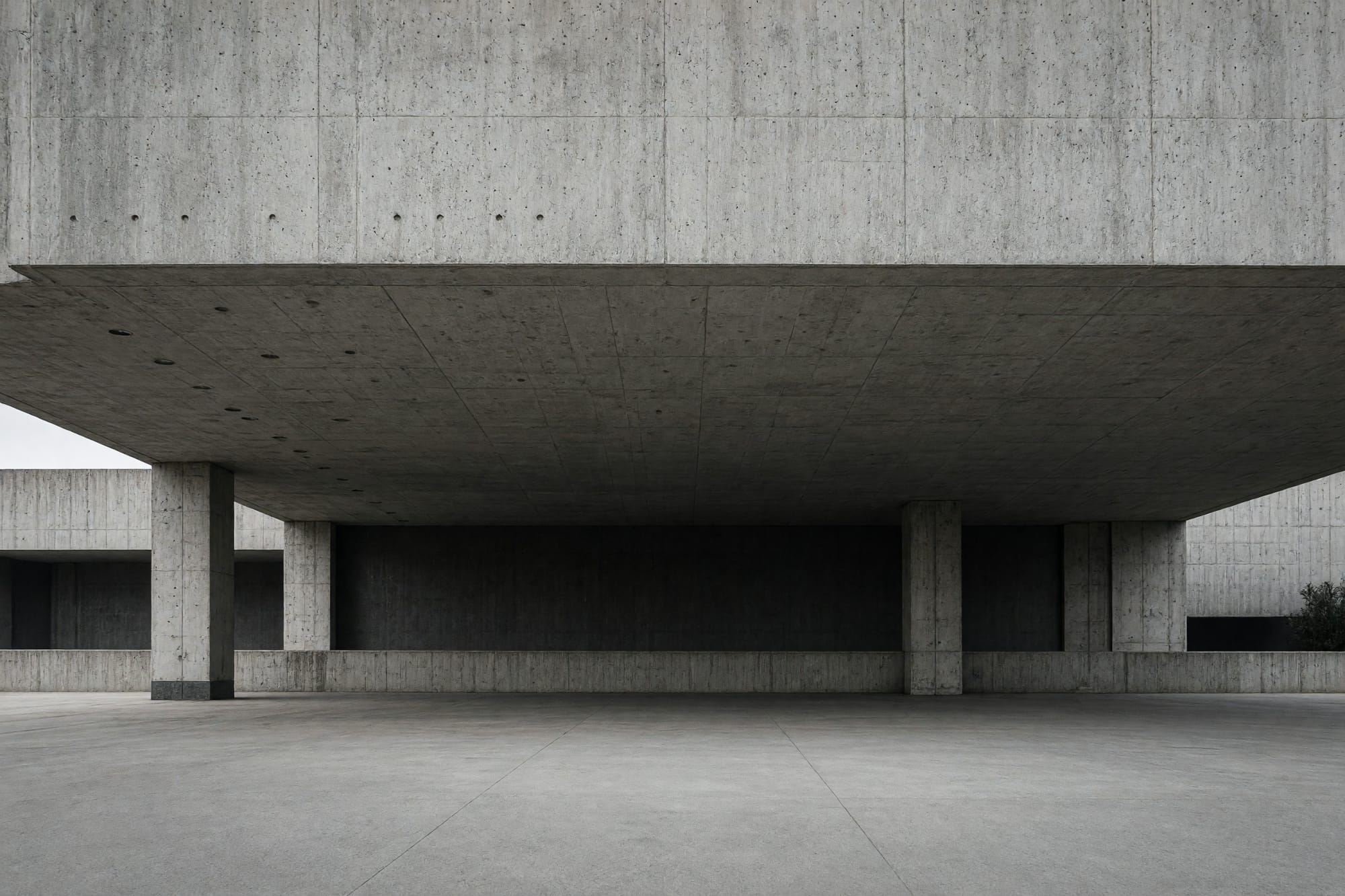 A cantilevered lecture theatre block projecting over a plaza, seen from beneath