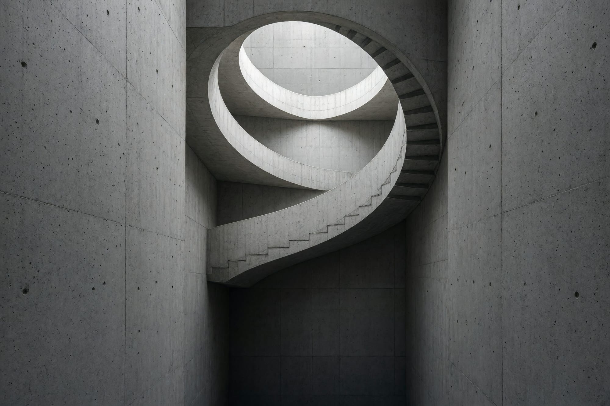 A concrete stair tower photographed from the ground looking directly up the well