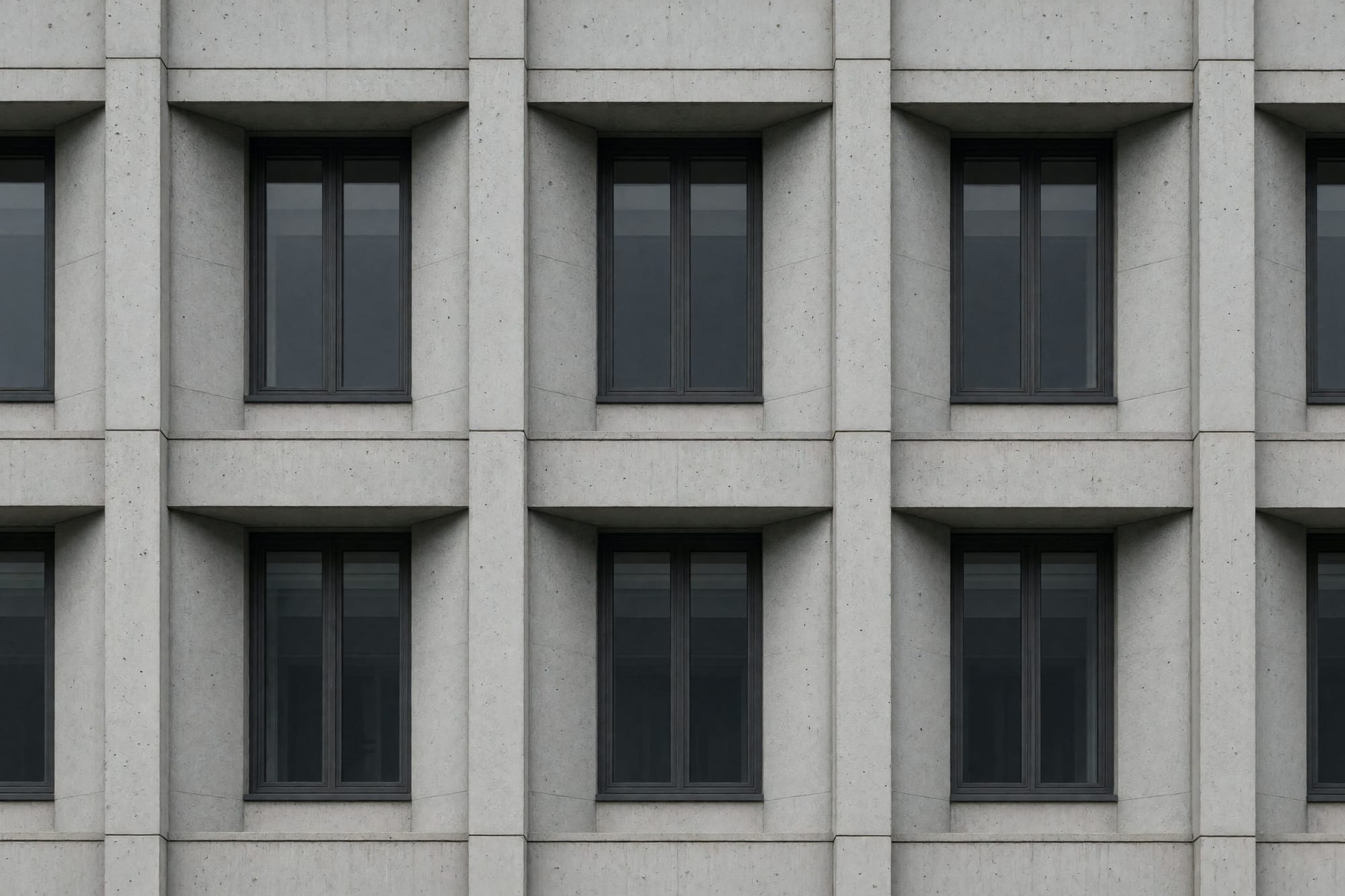 A run of precast window bays in oblique raking light with deep shadow in the reveals