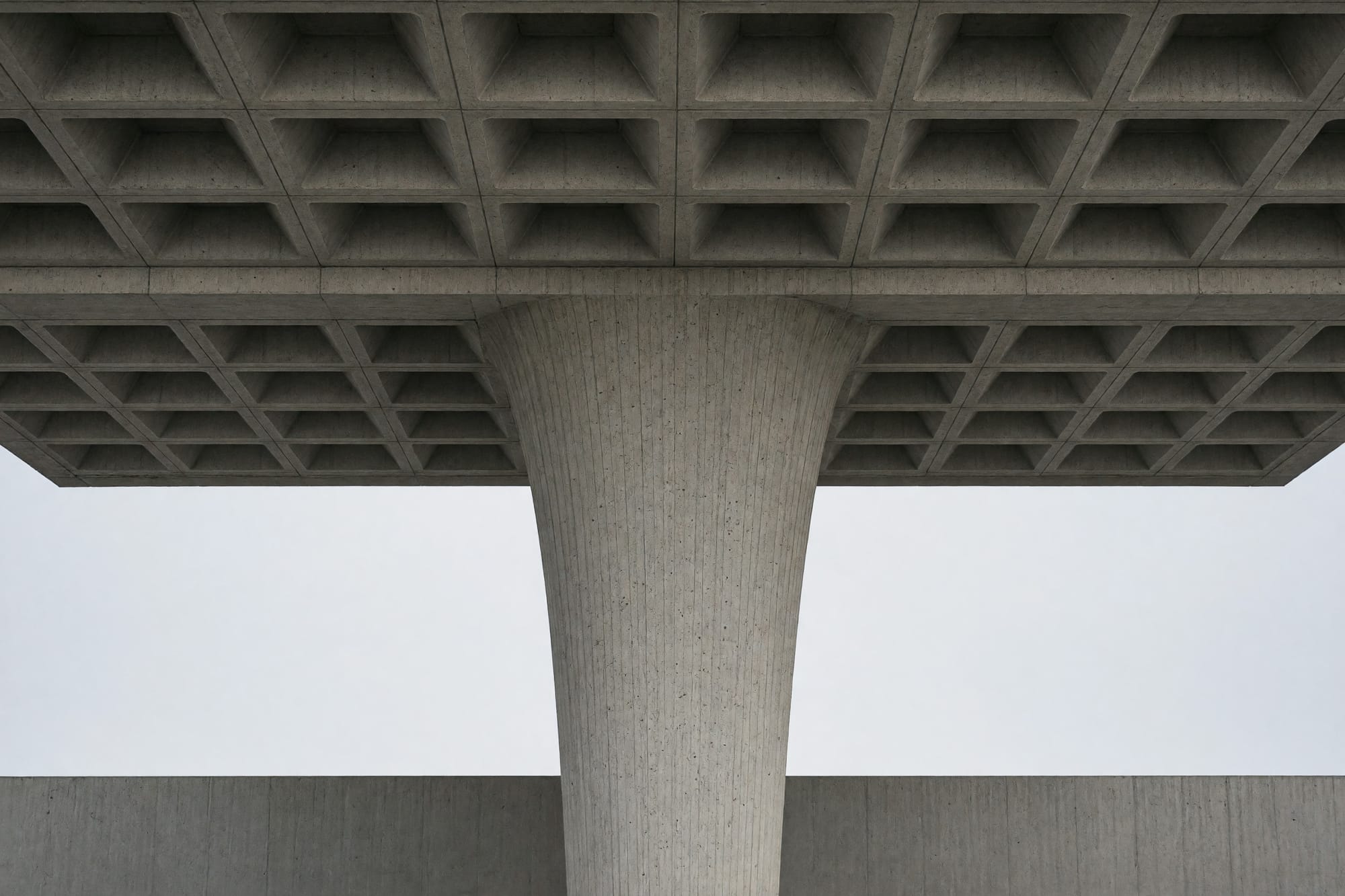 A single tapered column meeting a coffered soffit, board marking legible