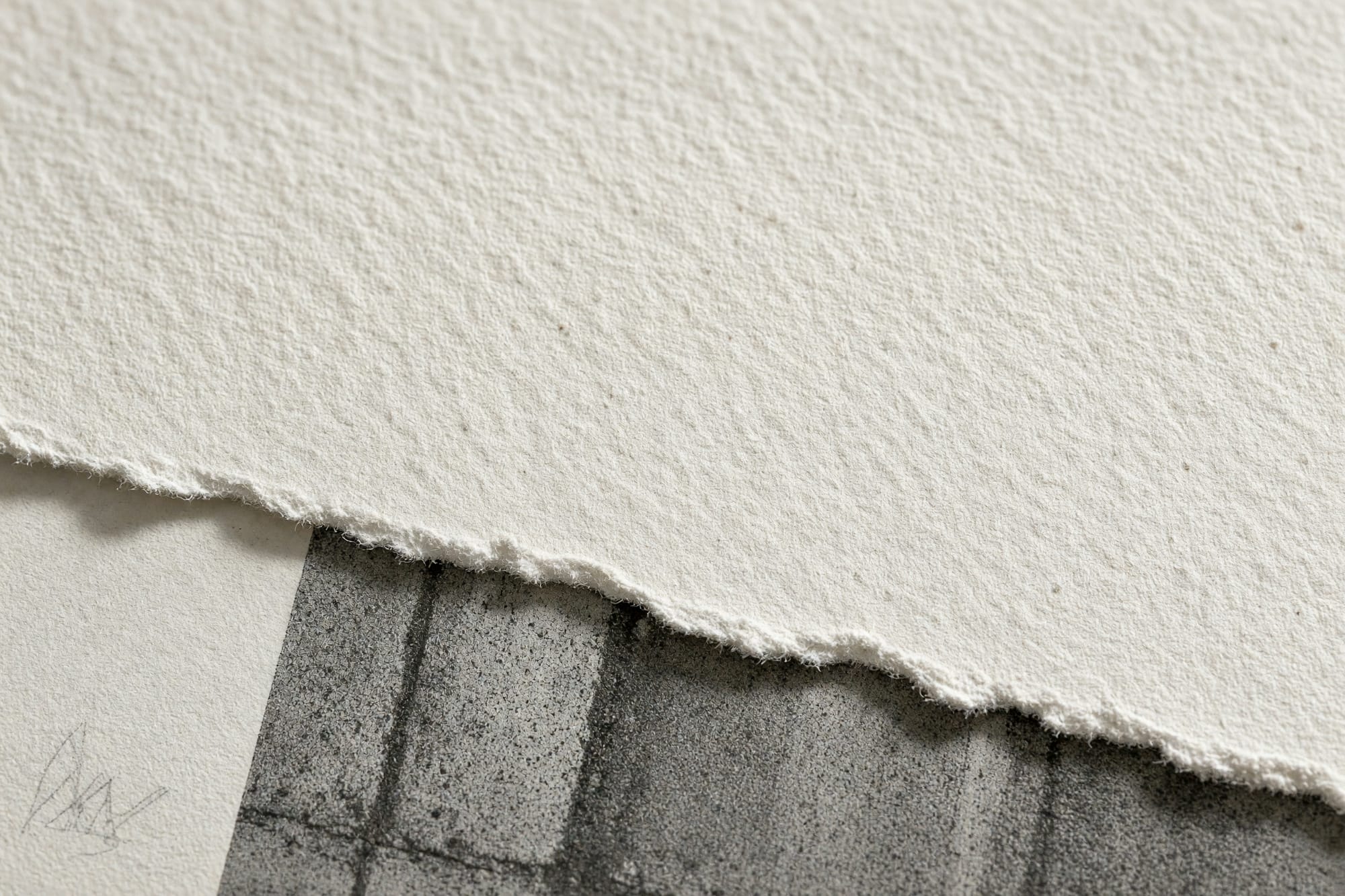 Macro of the cotton rag paper showing its tooth, a torn deckle edge and a pencil signature