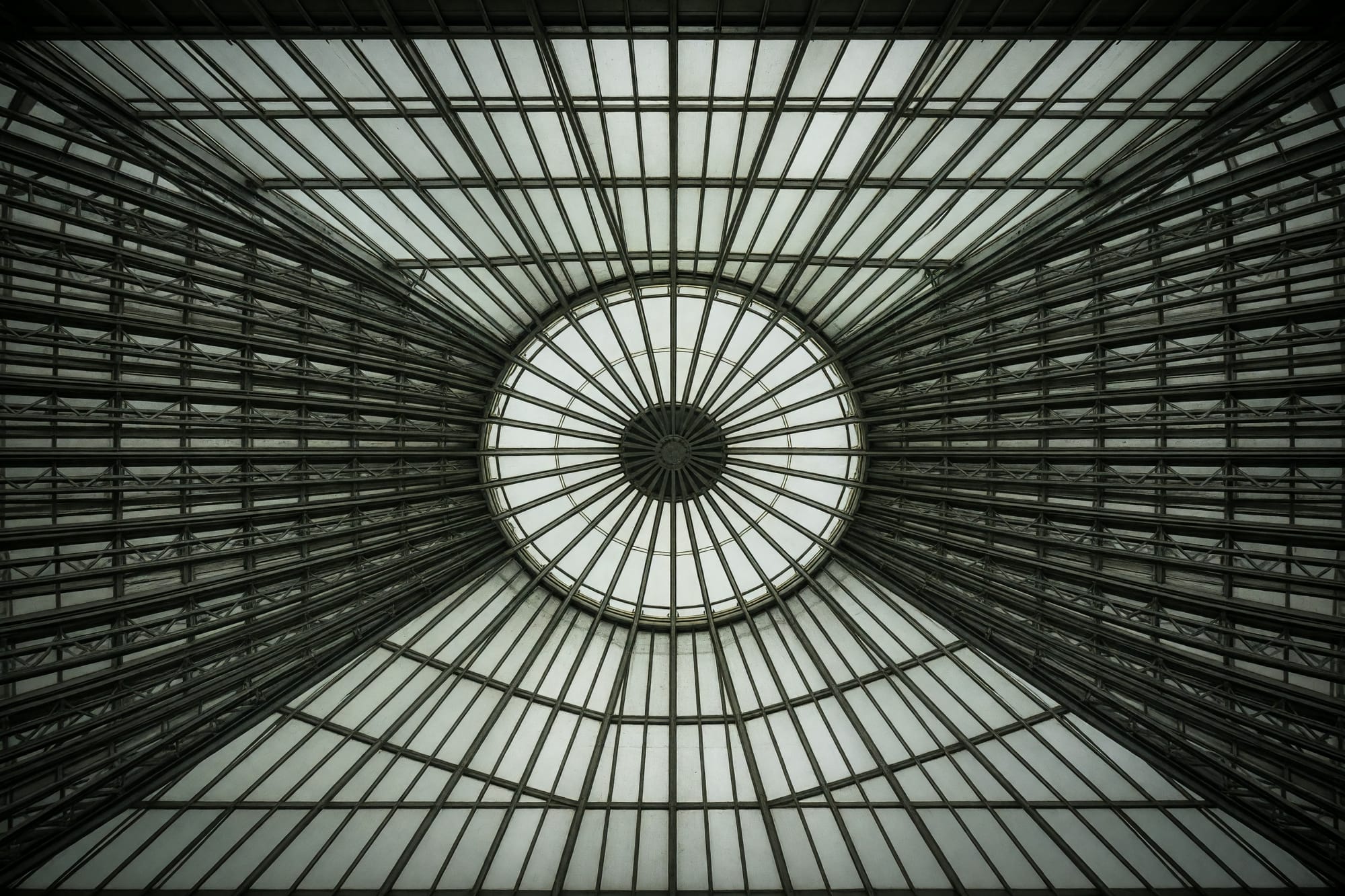 The apex of an iron and glass roof seen from directly below with the glazing bars radiating