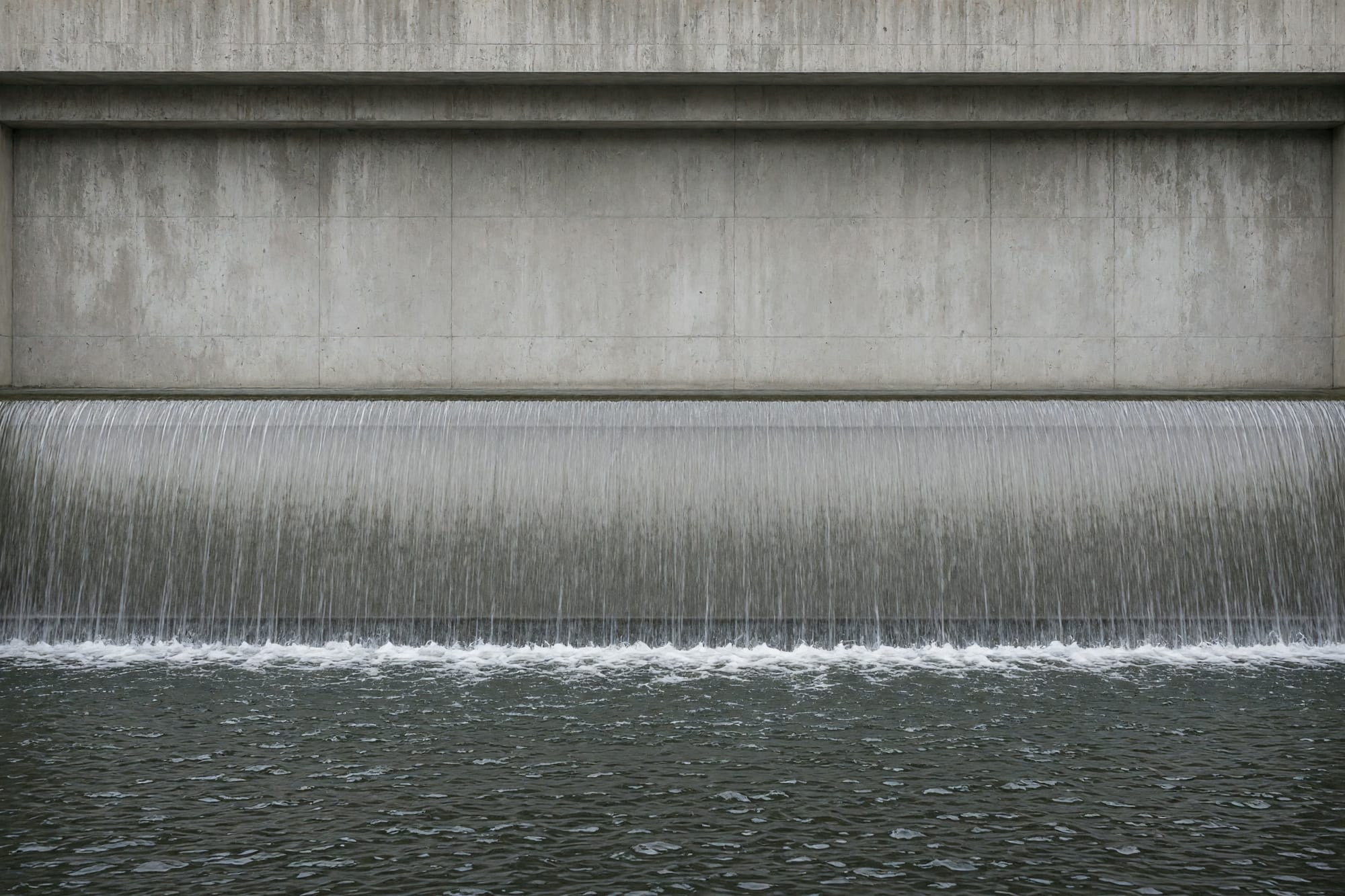 A concrete weir with a smooth unbroken sheet of water going over it