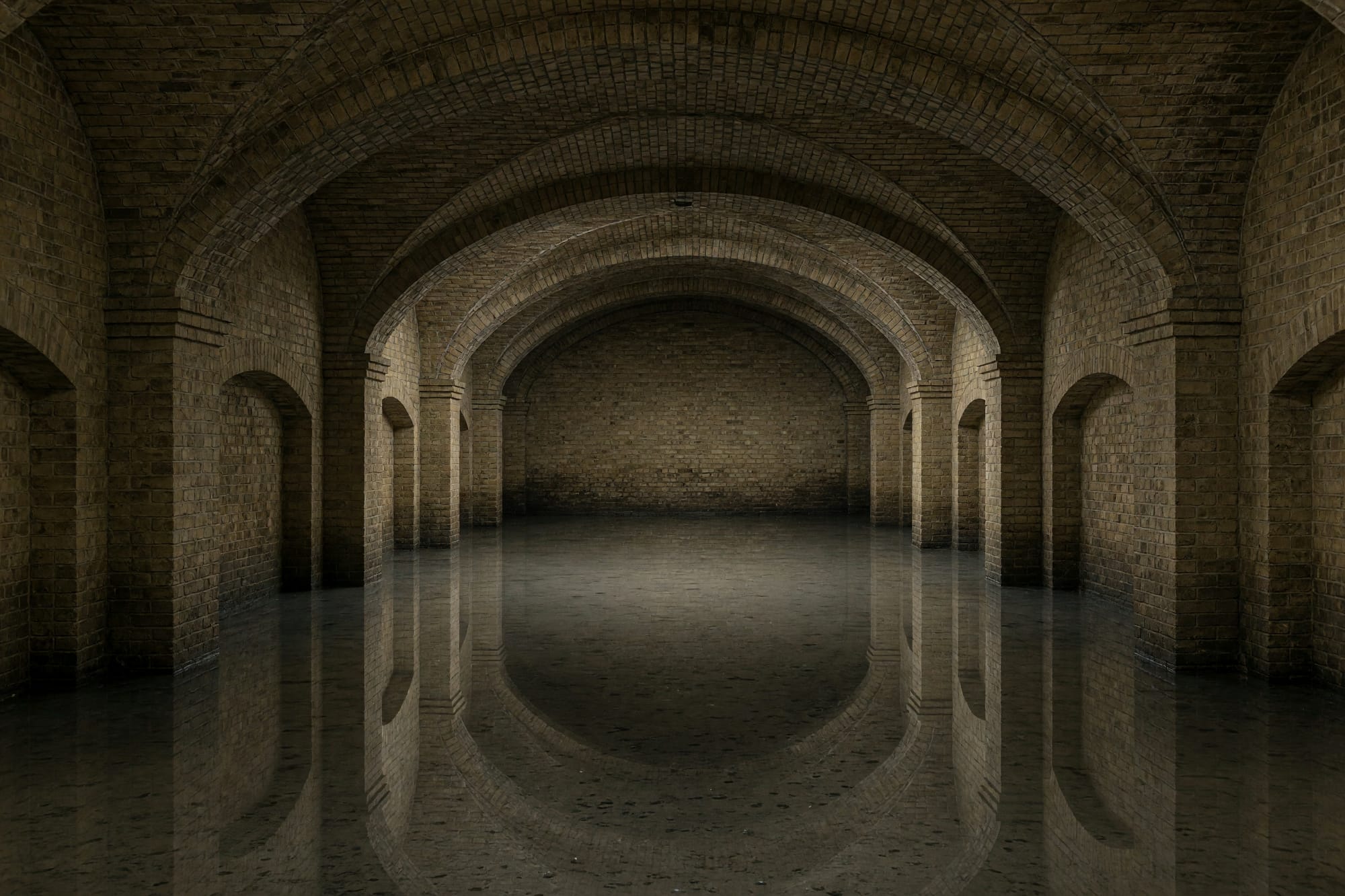 The interior of a Victorian covered reservoir, brick vaults reflected in shallow standing water